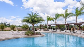 A swimming pool with lounge chairs and palm trees. - Beautifully Decorated Home, 10-minute drive from Disney, with Clubhouse. (Kissimmee)