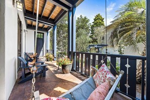 Un espacio al aire libre techado con techo de madera, un banco, una silla colgante y una planta en maceta.