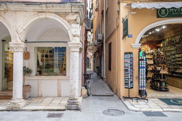 Una calle estrecha con una tienda a la derecha que exhibe varios artículos.
