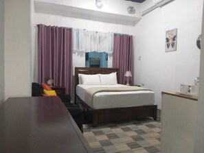 A hotel room with a bed, a desk, a chair, and a small table. - Sky Beach Rooms (Montego Bay)