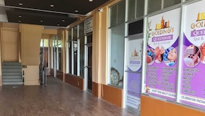 A hallway with a tiled floor, glass doors, and a sign for Golding's Queenstown Spa & Institute. - Sky Beach Rooms (Montego Bay)
