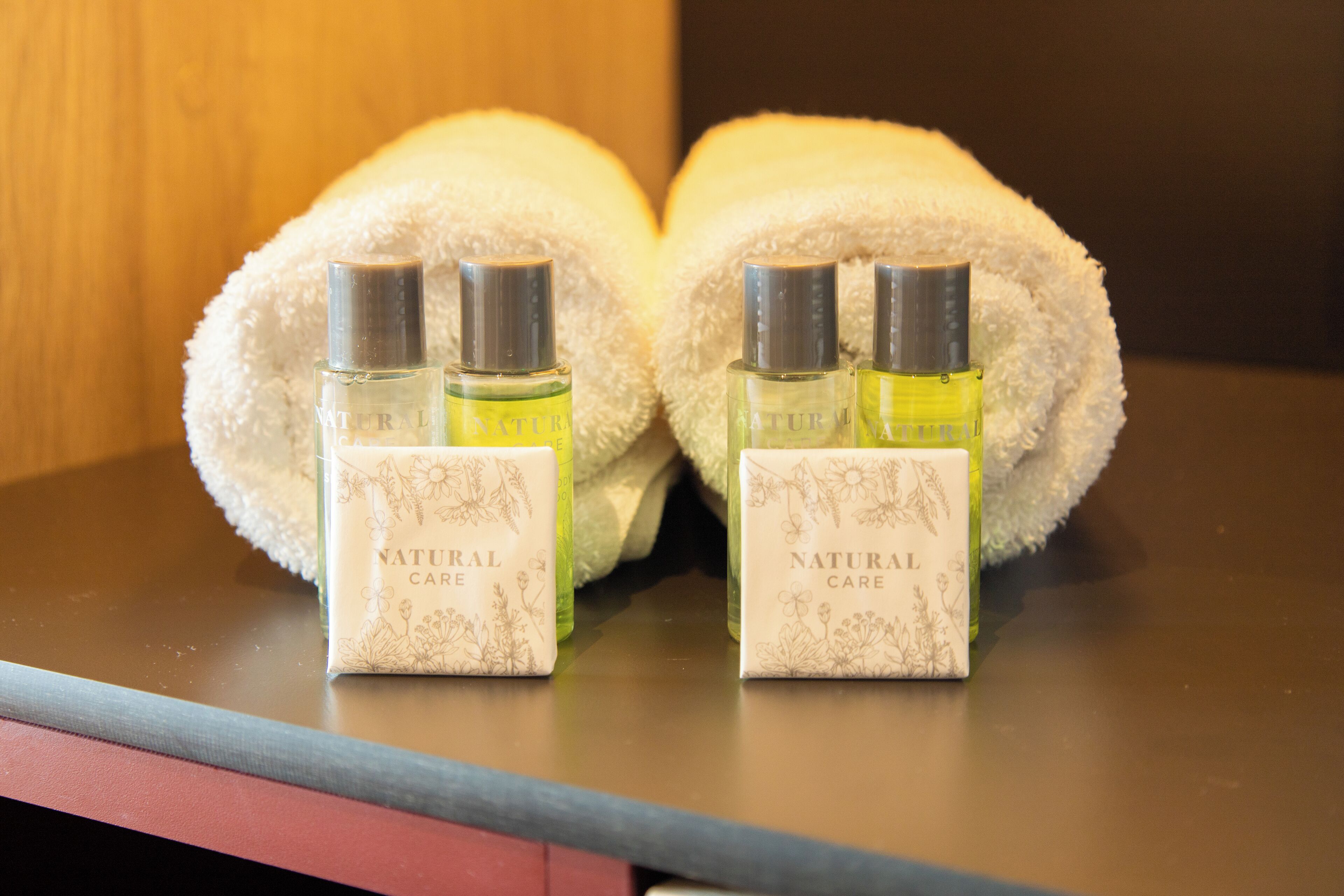 Two bottles of 'Natural Care' perfume and a white towel on a table.
