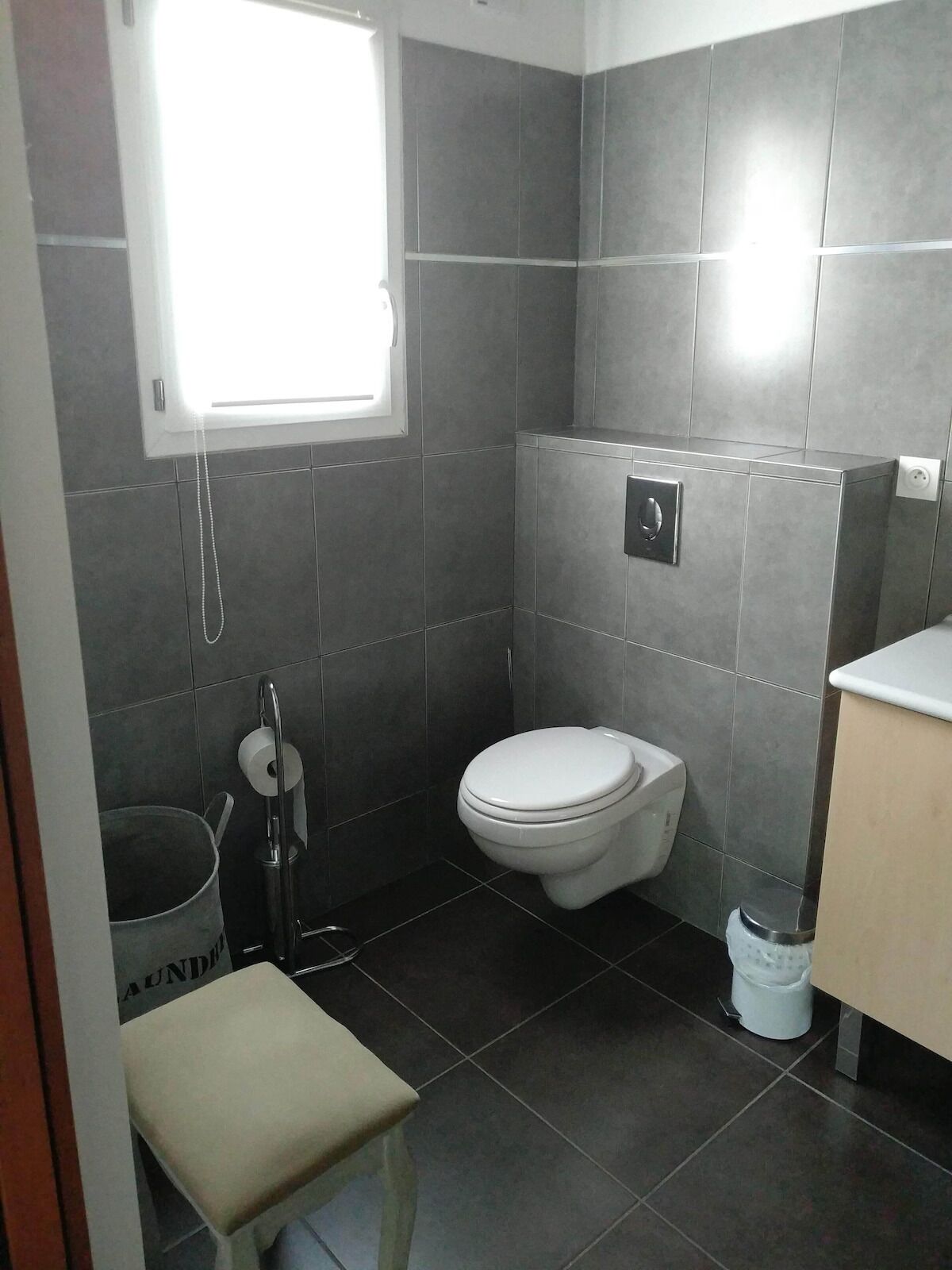 A small bathroom with a toilet, a sink, and a window.