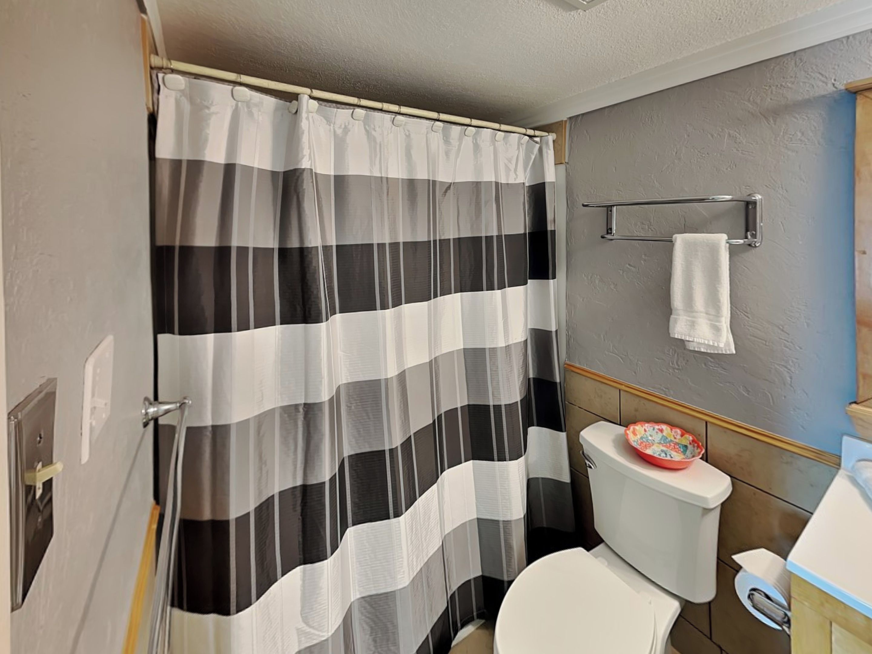 A bathroom with a striped shower curtain, a toilet, and a towel rack.