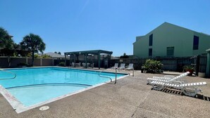 A rectangular swimming pool with a shaded area and lounge chairs. - Coastal Cozy and a View by Silver Sands Vacation Rentals (Corpus Christi)