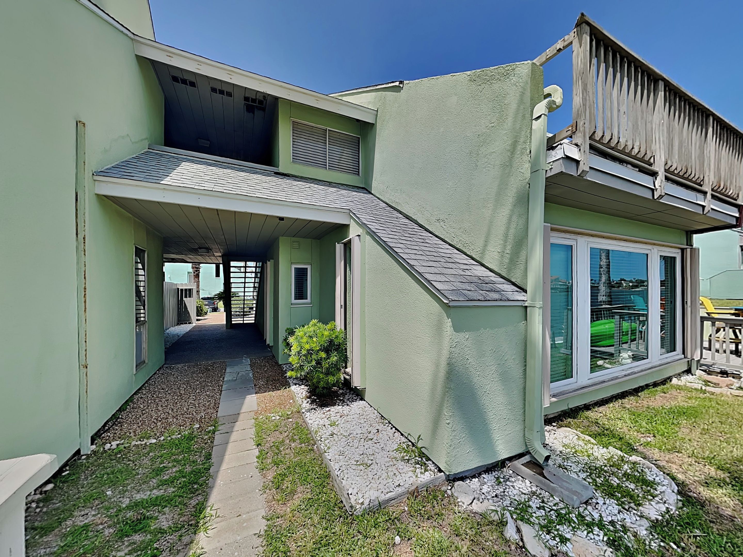 A two-story house with a covered walkway, a small garden, and a garage.
