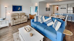 Ein modernes Wohnzimmer mit einem blauen Sofa, beigen Sesseln und einem weißen Couchtisch.