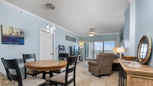 A spacious living area with a dining table, chairs, a sofa, and a TV.