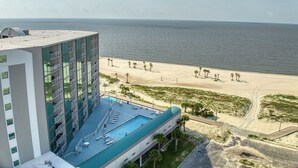 A hotel with a rooftop pool, a beach view, and a sandy beach area.