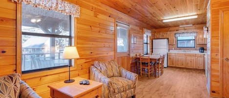 A cozy cabin interior with wooden walls, a dining area, and a kitchen.