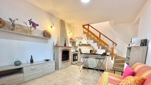 Una sala de estar acogedora con chimenea, una zona de cocina y una escalera.