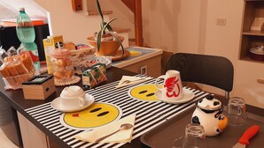 Una mesa de comedor con mantel a rayas, una tetera, una taza y un plato con diseño de carita sonriente.