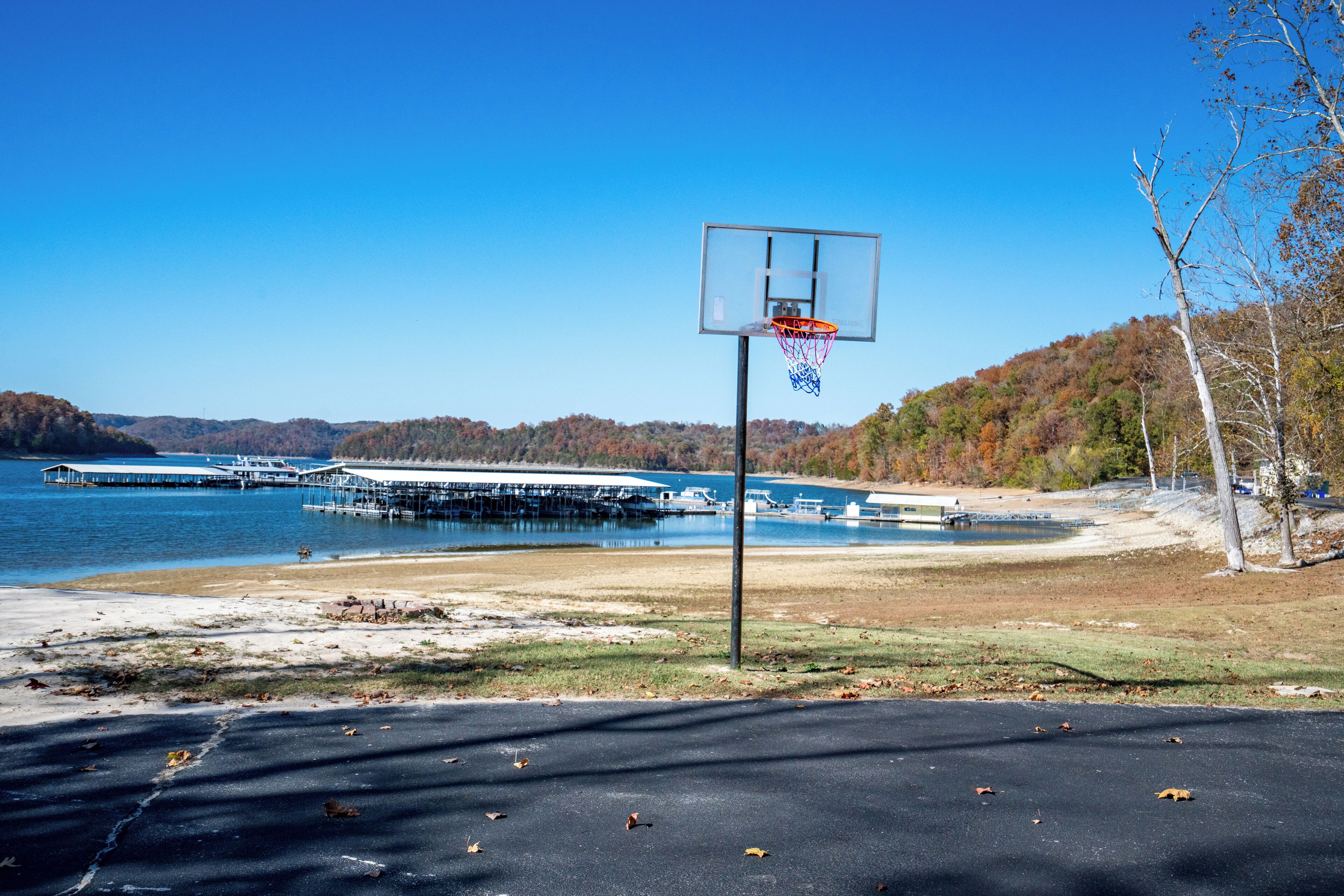 Una cancha de baloncesto con vista despejada a un lago y estructuras de embarcadero al fondo.