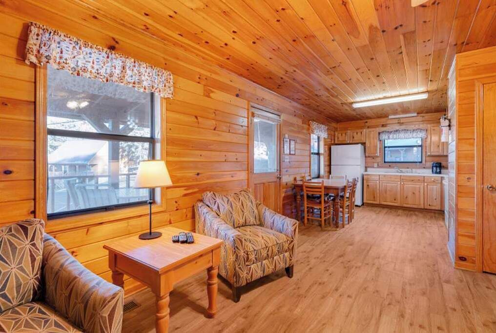 A cozy cabin interior with wooden walls, a dining area, and a kitchen.