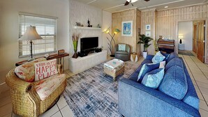A living room with a sofa, a television, a fireplace, and a bookshelf.