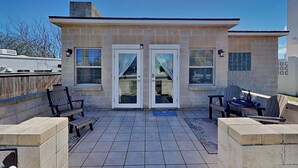 A patio area with a stone wall, two doors, and outdoor seating.