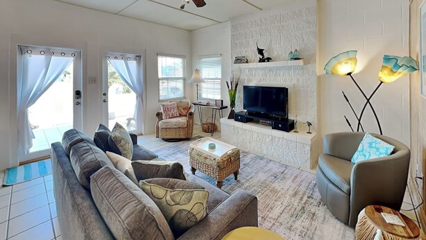 A living room with a sofa, armchairs, a TV, and a fireplace.