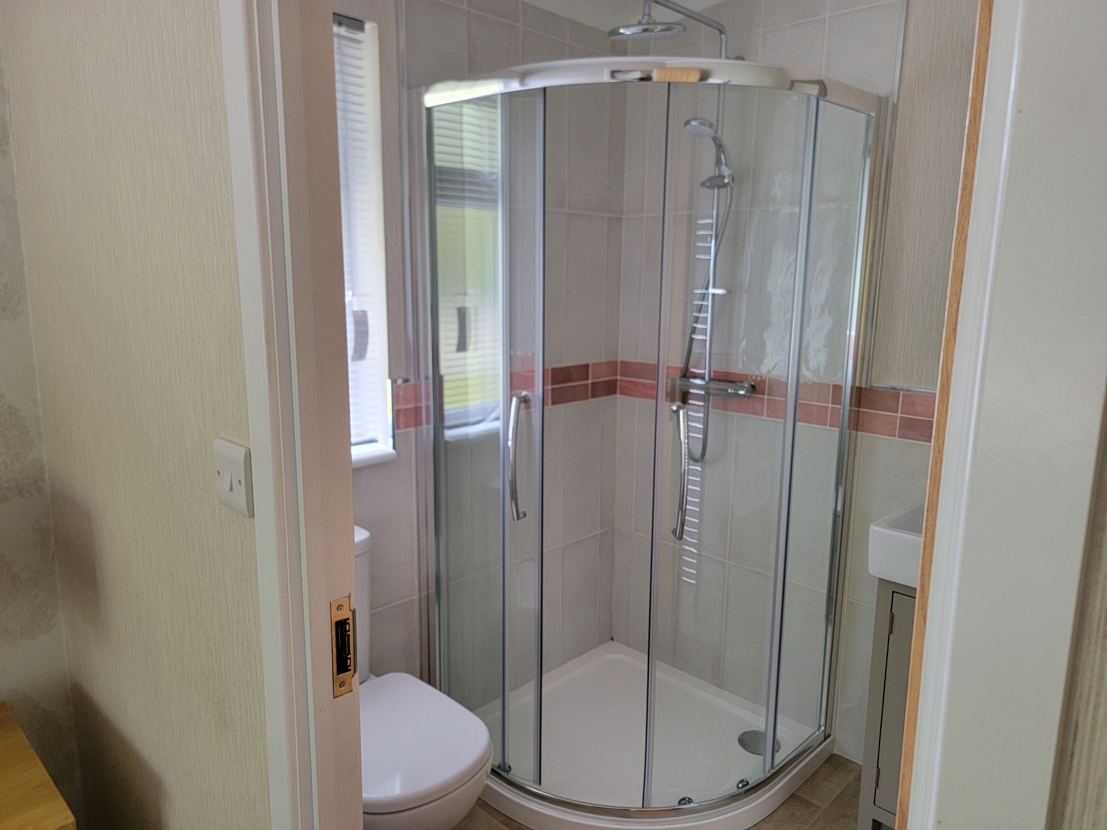 A glass-enclosed shower stall with a toilet adjacent to it.