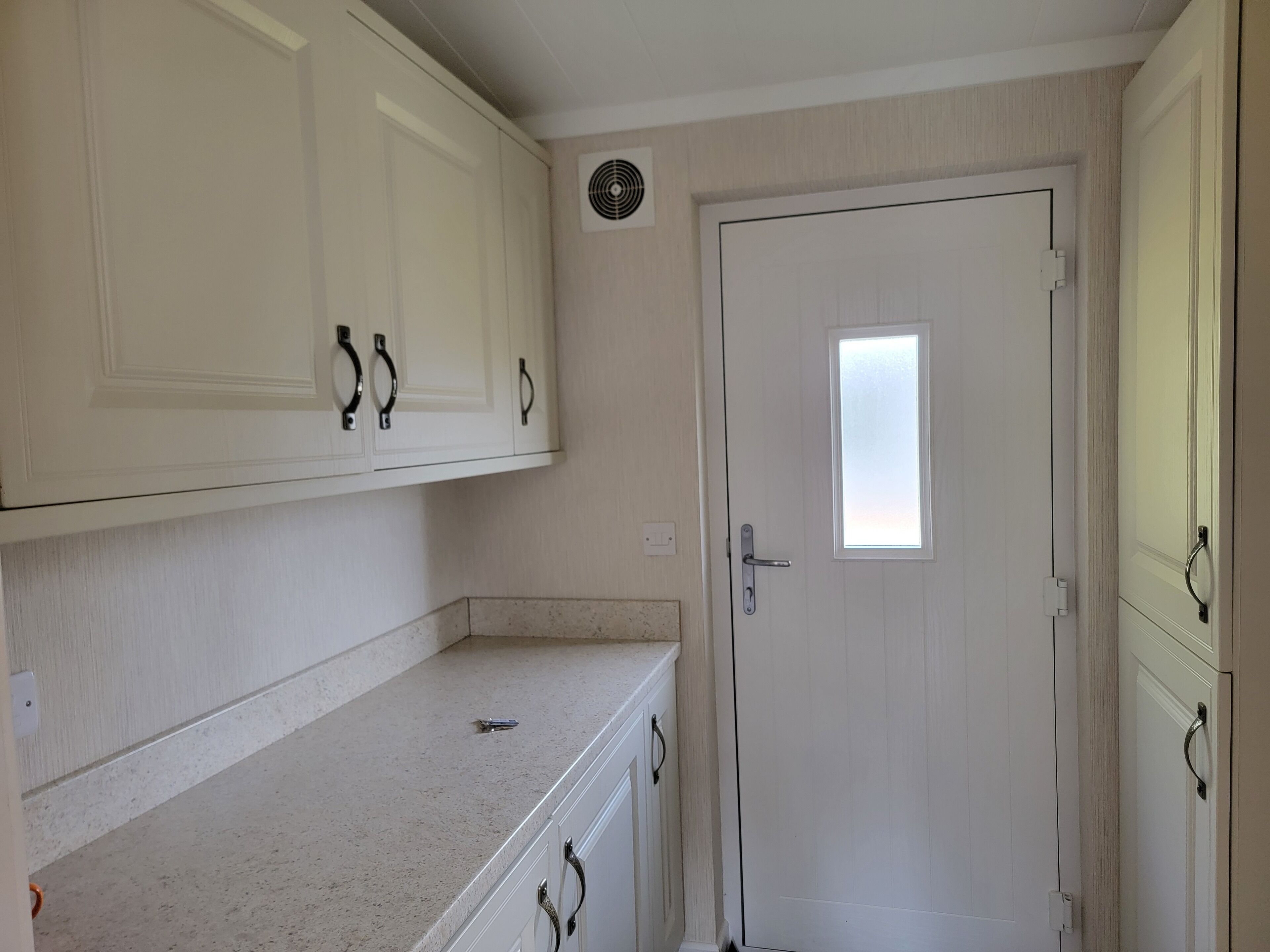 A small, compact kitchen with white cabinets and a single window.