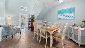 A dining area with a wooden table, white chairs, a ceiling fan, and a painting on the wall. - 2 Homes Together|Sleeps 16|Walk 2 Beach|Firepit (Cocoa Beach)