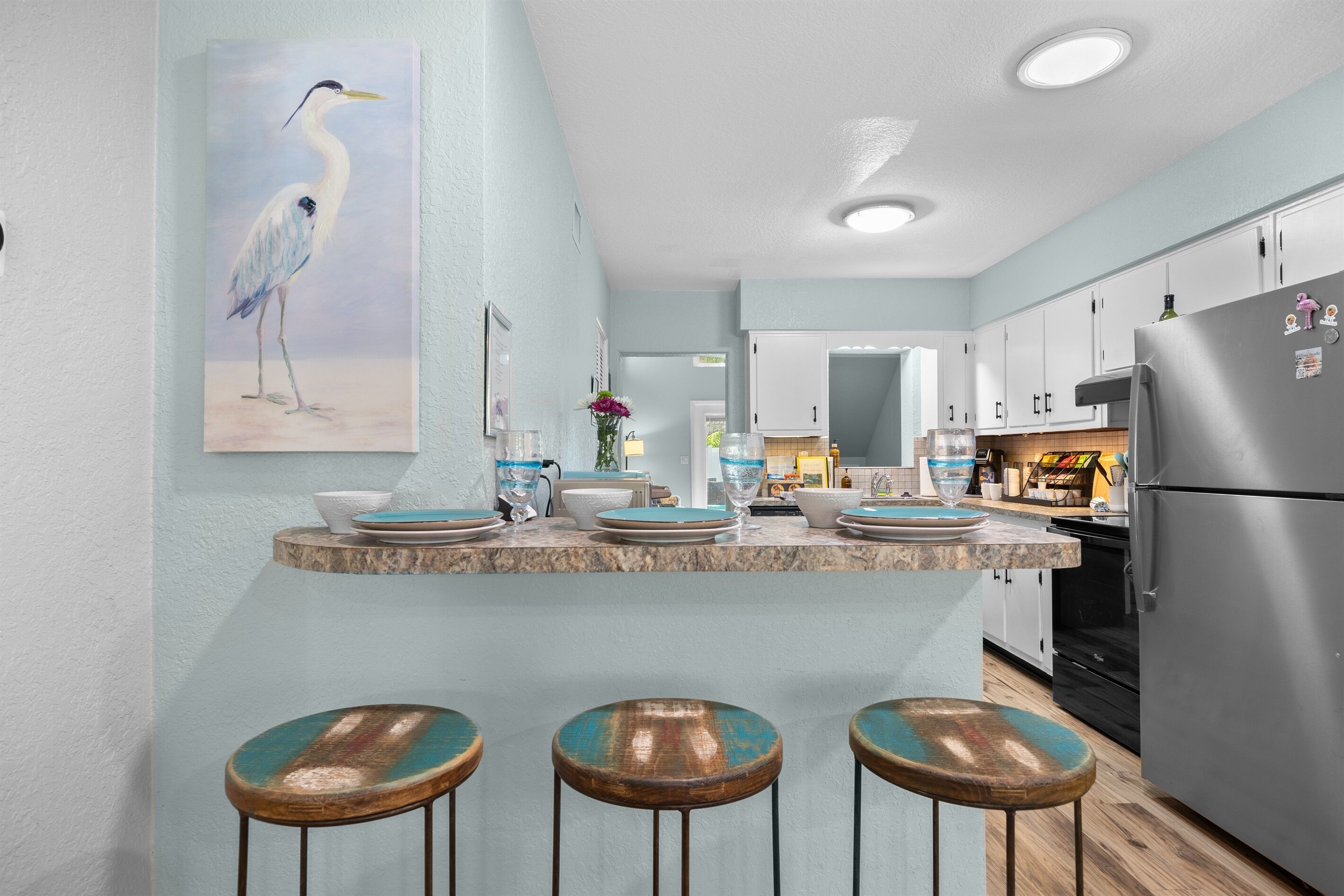 A kitchen with a central island, bar stools, and a refrigerator.