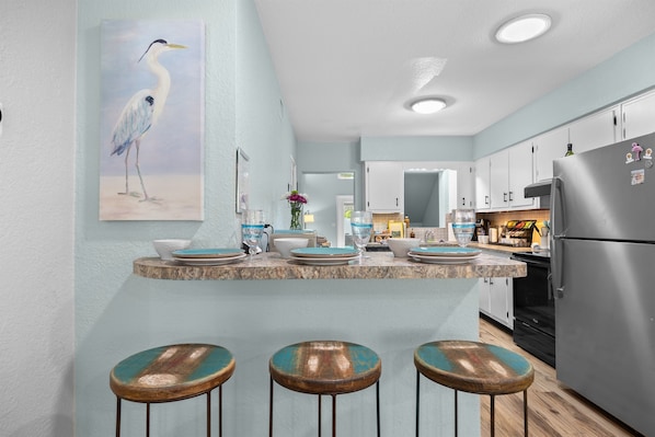 A kitchen with a central island, bar stools, and a refrigerator.