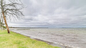 A riverside walkway with a grassy area and a tree. - Family-Friendly Houghton Lake House: Steps to Lake (Houghton Lake)