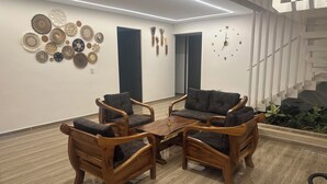 Een moderne woonkamer met houten meubels, een wandklok en decoratieve borden.