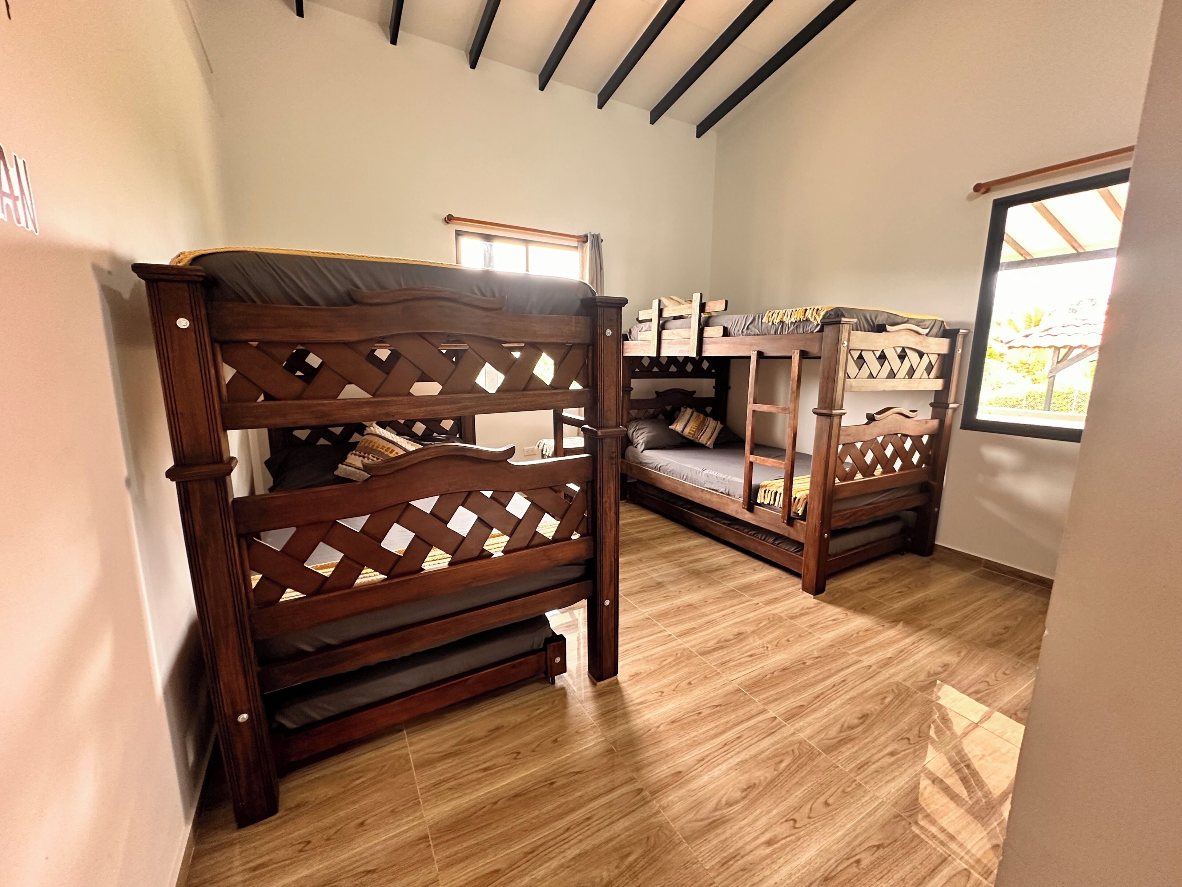 Dos literas de madera con paneles de celosía en una habitación con suelo de madera y techo inclinado.
