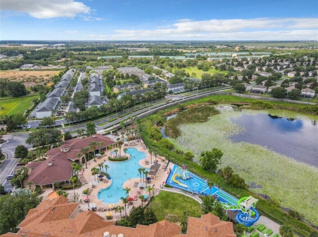 Luchtbeeld van een resort met een groot zwembad, een waterpark en een meer.