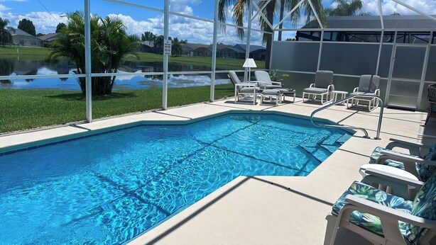 A swimming pool with lounge chairs and a view of a lake and palm trees. - EP1051SEL - Private Vacation Pool Home Near Disney (Kissimmee)