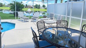A covered outdoor area with a pool, lounge chairs, and a table. - EP1051SEL - Private Vacation Pool Home Near Disney (Kissimmee)