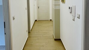 A hallway with wooden flooring, white walls, and a closed door at the end. - La trinacria (Syracuse)