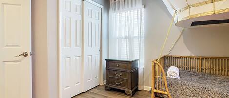 Une chambre avec un lit superposé, une commode, une armoire et un plafond décoré d’un ciel peint.