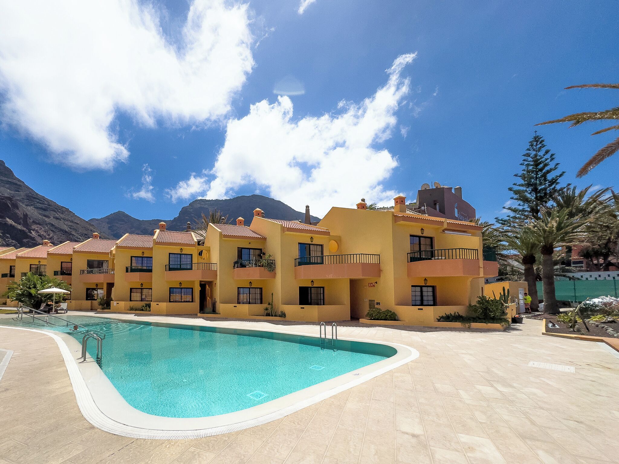 Un hôtel doté d’une piscine, de nombreux balcons et offrant une vue sur un paysage montagneux.