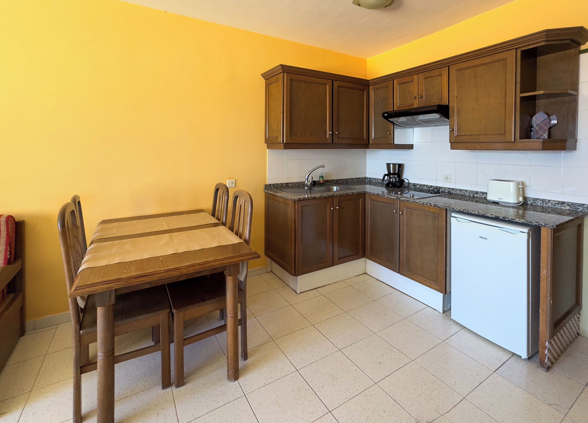 A compact kitchen with wooden cabinets, a built-in stove, and a small refrigerator.