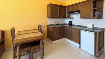 A compact kitchen with wooden cabinets, a built-in stove, and a small refrigerator.