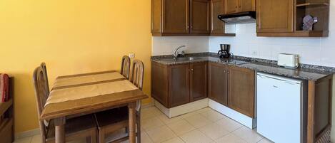 A compact kitchen with wooden cabinets, a built-in stove, and a small refrigerator.