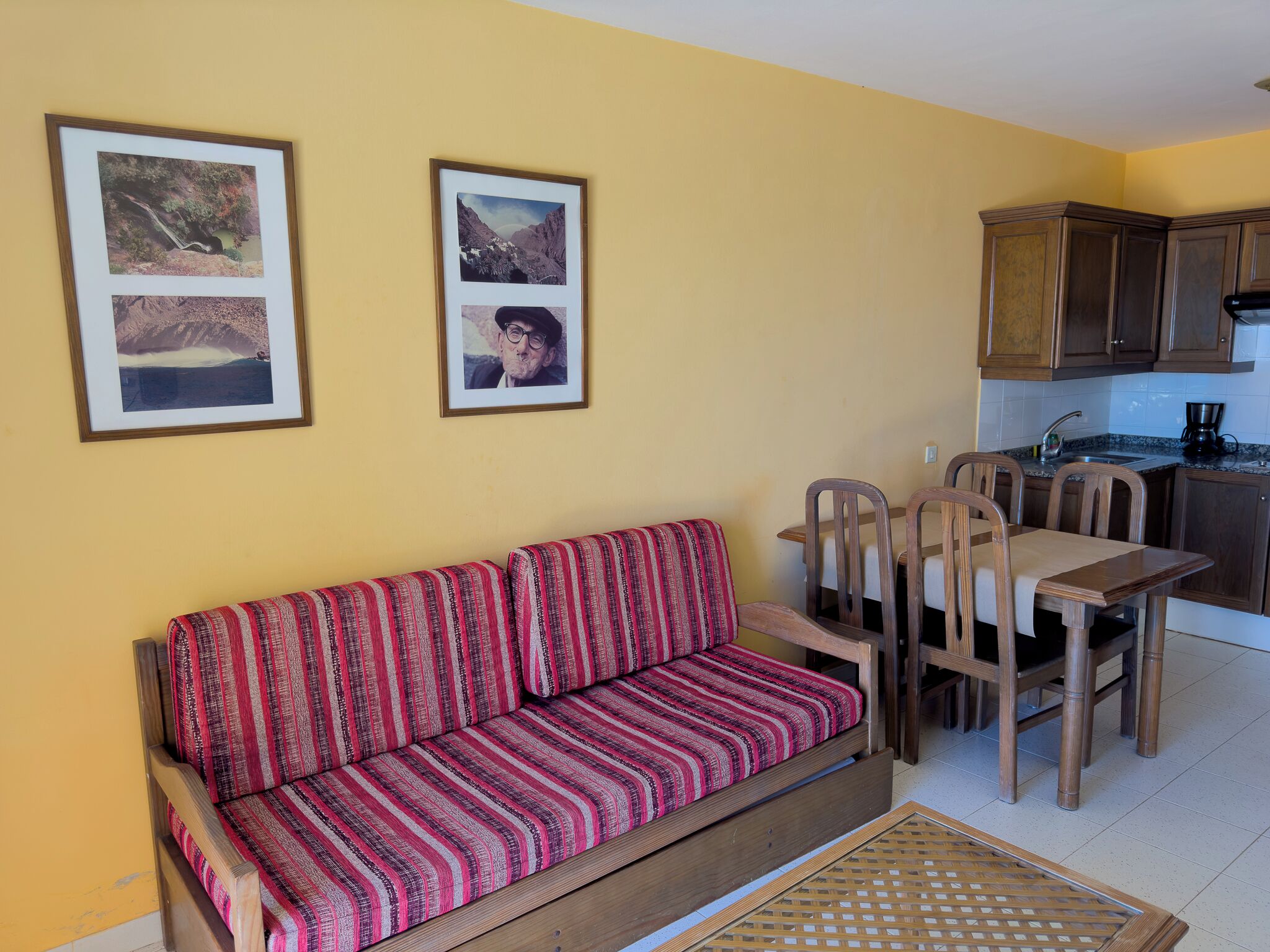 A cozy living area with a sofa, dining table, chairs, and a kitchen area with cabinets and a sink.