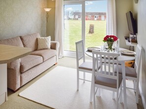 Un salon confortable avec un canapé, une table à manger et des chaises, et une vue sur l’extérieur.