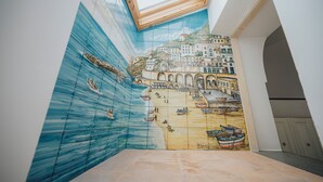 Een kamer met een muurschildering van een kustlandschap met boten en gebouwen.