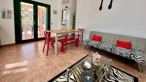 A modern living room with a dining area, a sofa with zebra print, and a wall-mounted spoon and fork decoration. - Residence Skipper (San Teodoro)