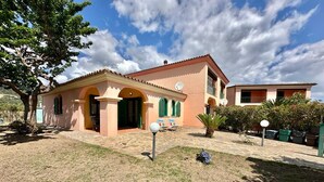 A two-story house with a tiled roof, a small porch, and a well-maintained lawn. - Residence Skipper (San Teodoro)