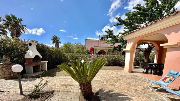 A patio area with a stone floor, a palm plant, a barbecue grill, and a lounge chair. - Residence Skipper (San Teodoro)