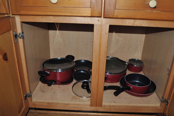 A wooden cabinet with multiple pots and pans, some with lids. - Lakeside 3 bedroom chalet with hot tub!! (Byrdstown)