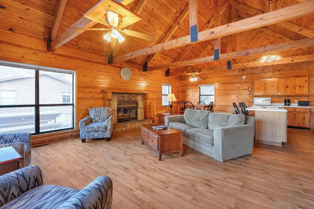A spacious cabin with a wooden interior, a fireplace, a dining area, and a kitchen.