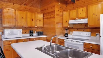 A modern kitchen with wooden paneling, stainless steel appliances, and white countertops.