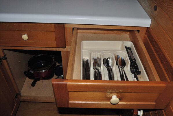 Un cajón con utensilios de cocina y una olla.