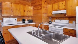 Een moderne keuken met houten lambrisering, roestvrijstalen apparatuur en witte aanrechtbladen.