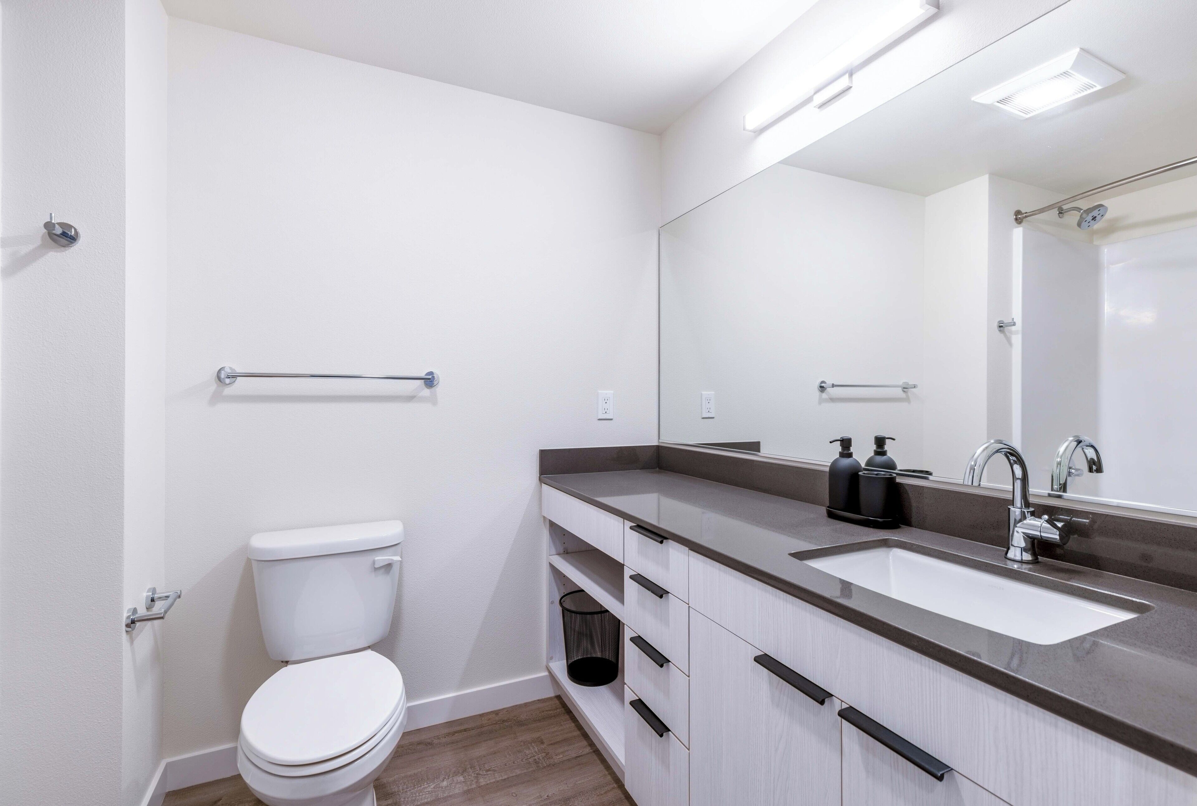 Un baño moderno con un inodoro blanco, un lavabo con un espejo encima y una zona de ducha.